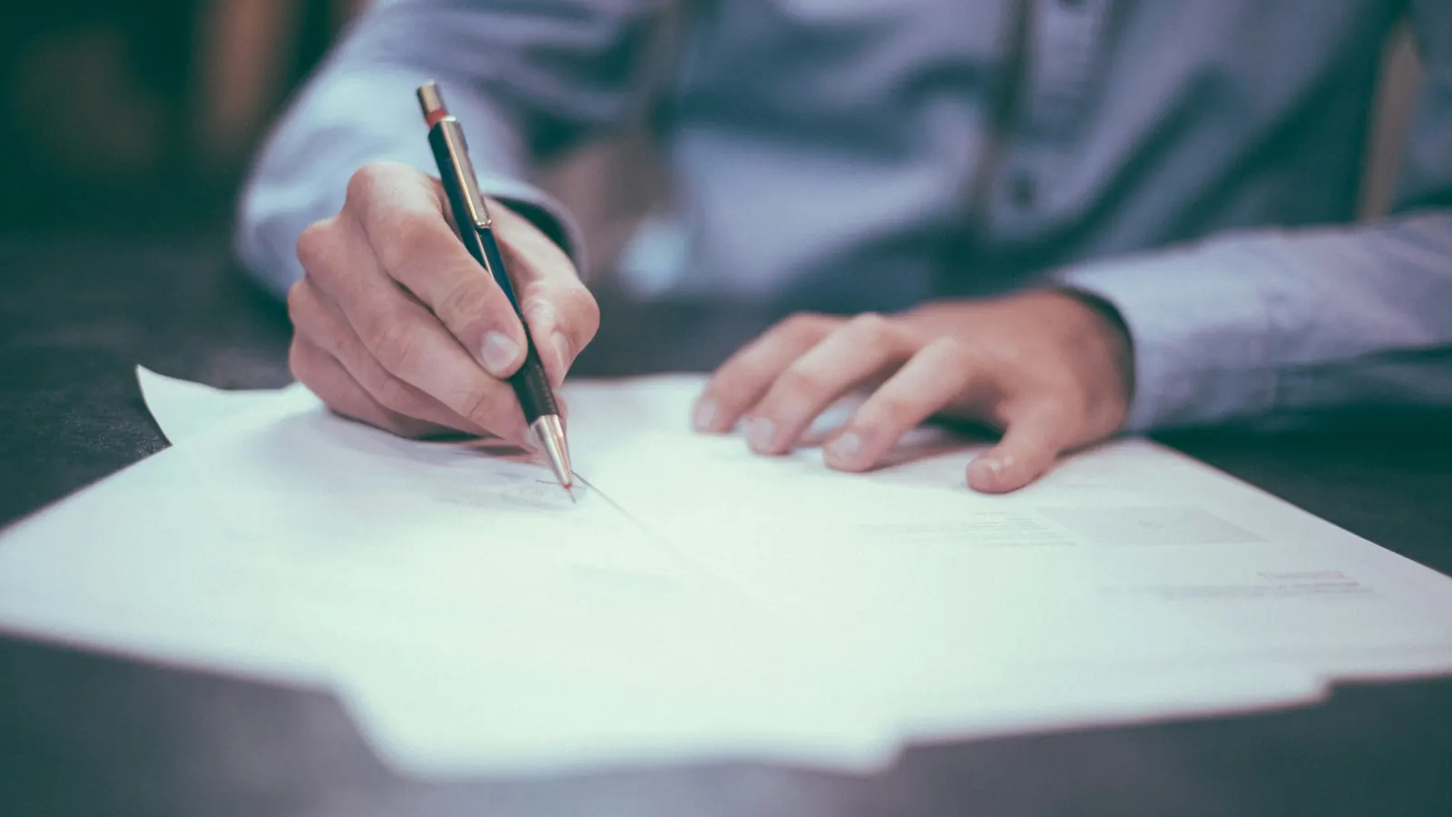 A person signing a document at a desk