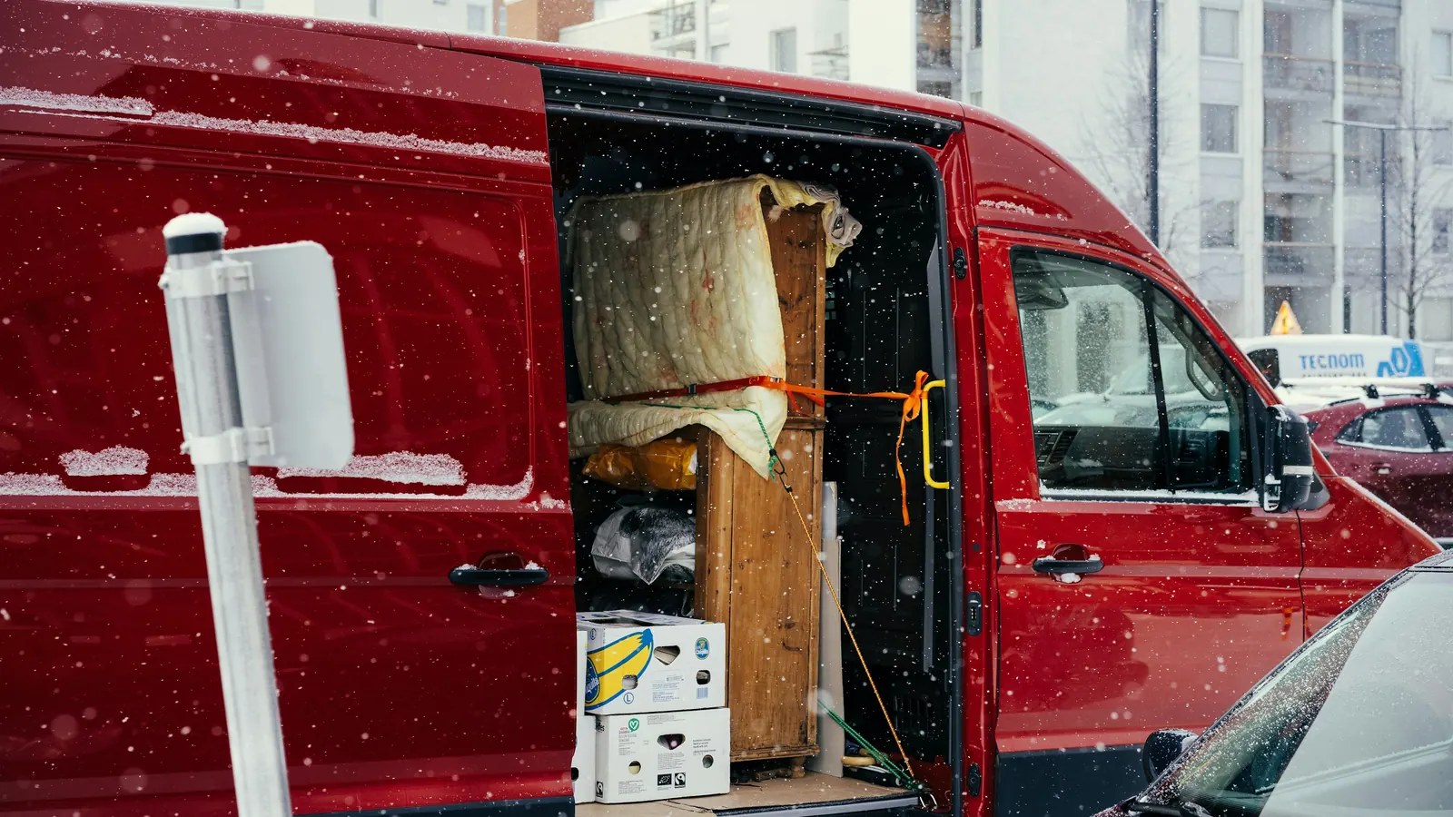 A red van with its side door open, loaded with furniture and boxes